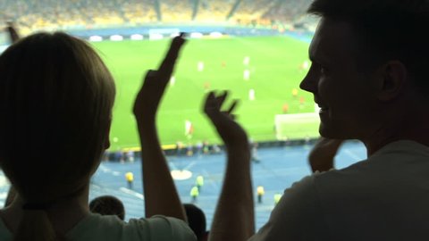 Couple applauding during football game, positive emotions when watching match