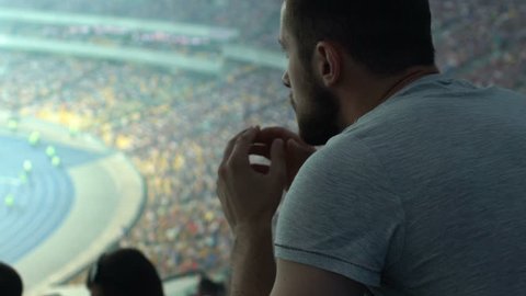 Male supporter watching sport game at stadium, concentrated and agitated, worry
