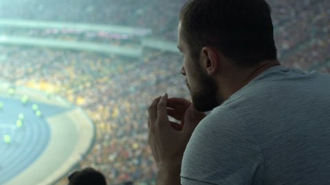 Male sport fan jumps in disappointment, watching match or races at stadium