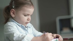 Adorable young girl playing alone on kid's tablet at home