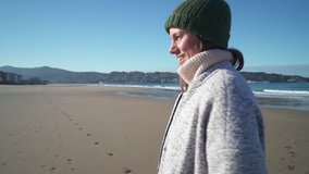 Lovely happy woman walking on sunny beach in winter