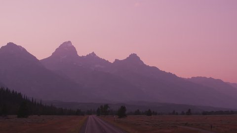 Driving along road in Grand Teton National Park at sunset