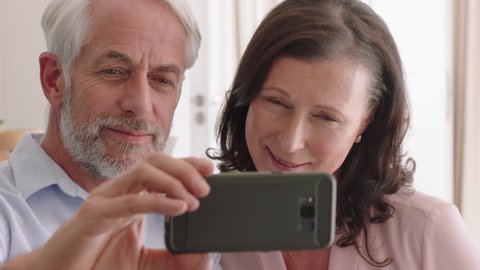 happy middle aged couple using smartphone having video chat waving at grandchildren enjoying online communication relaxing retirement home
