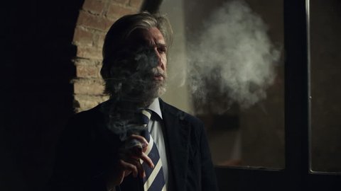 Dangerous Mafia gangster smoking expensive Cuban cigar while wearing an expensive Italian suit. 
