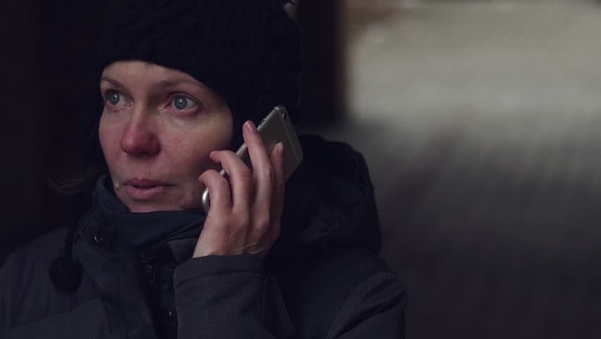 Concerned worried woman talking on mobile phone on street on cold winter day | Shutterstock HD Video #1022620540