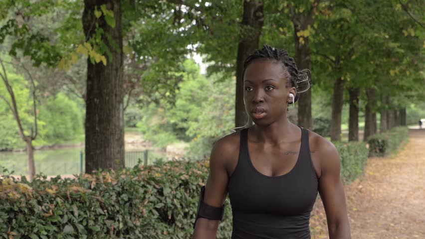 Confident beautiful young athlete walking in the park.Sport,training-slow motion