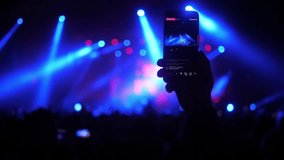People taking video and photos on mobile smart phone at concert party crowd