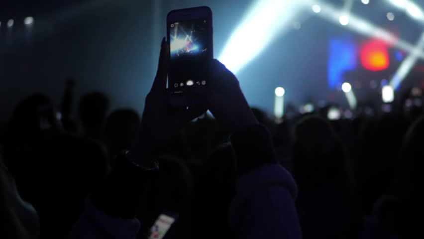 People taking video and photos on mobile smart phone at concert party crowd