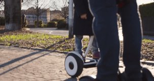 segway detail with daughter child and dad riding.Modern future transport technology.Active Family.Park sidewalk urban outdoor.Warm sunset cold weather backlight.4k slow motion 60p video