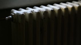 Detail with a hand checking the heat coming from a household radiator 