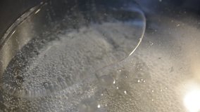 Water with olive oil boiling in black pot. Abstract close-up on the surface of boiling water.