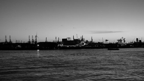 HAMBURG, GERMANY - CIRCA 2018: Stage Theater im Hafen at dusk with spectacle Mary Poppins and industrial pipes gas and oil factories in background - black and white