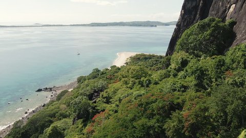 Aerial of Nosy Ankarea Madagascar over the forest past massive granite hill approaching the beach, near Nosy Be