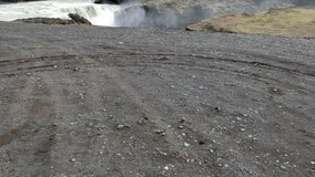 Iceland, aerial survey. Waterfall Sigoldufoss. Black land, volcanic land, flight over the waterfall.