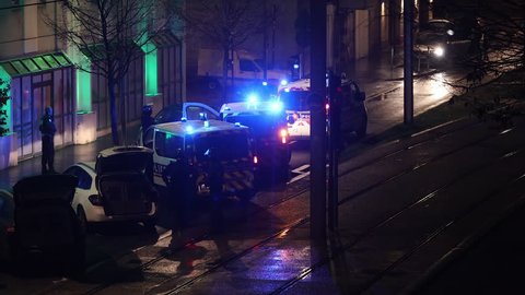 Bordeaux, France - January 2019 : French policemen standing around French police vehicles parked with blue lights and lighted sirens on during yellow vests movement and riots in France at night