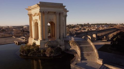 Beautiful sunlight flare flying over water tower in Montpellier Peyrou parc aerial drone shot
