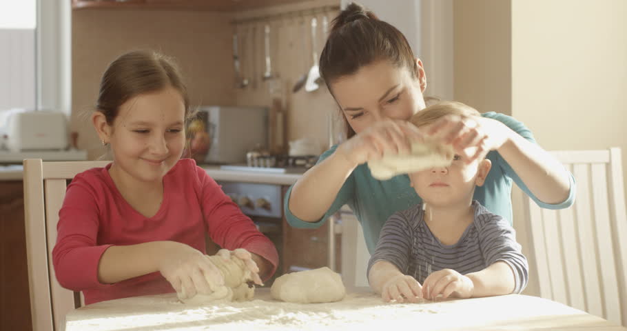Smiling Happy Family Playing with Dough Banging on the Flour on the Table in the Kitchen Cooking Together Cookies. Cheerful Mother Son and Daughter Having Fun and Good Time on a Sunny Day Royalty-Free Stock Footage #1022663350