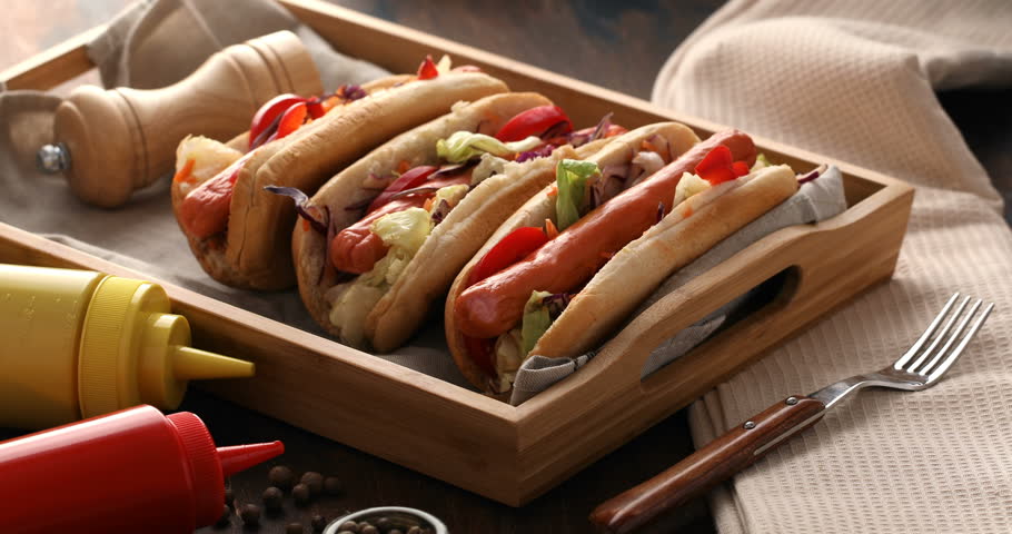 Hot dogs with a sausage on a fresh rolls garnished with mustard and ketchup. Men hand hand pouring hotdog with sauce Royalty-Free Stock Footage #1022665183