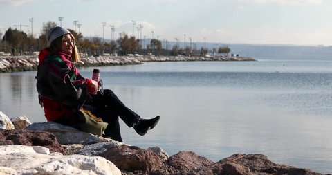 Middle age woman with winter clothing sitting on the shore line and relaxing at the outdoor