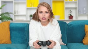 Happy young woman playing video games in living room.
