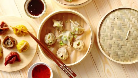 Traditional chinese dumplings served in the wooden bamboo steamer over raw wooden background table. Top View composition.