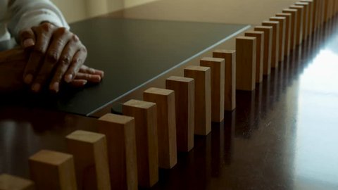Problem Solving,Close up view on hand of business woman stopping falling blocks on table for concept about taking responsibility. 
