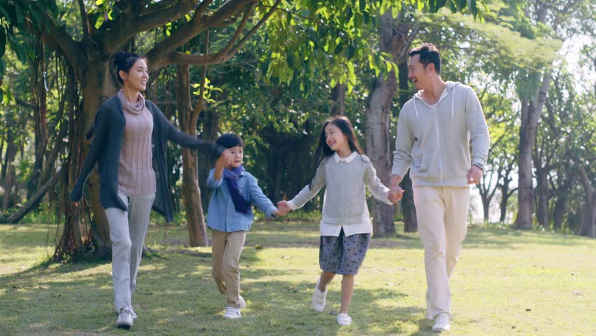 Asian family with two children walking hand in hand having fun in park