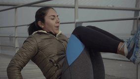 Slow motion shot of concentrated hindu brunette woman training on jetty. Thoughtful sportswoman during outdoor workout at seaside. Concept of sport
