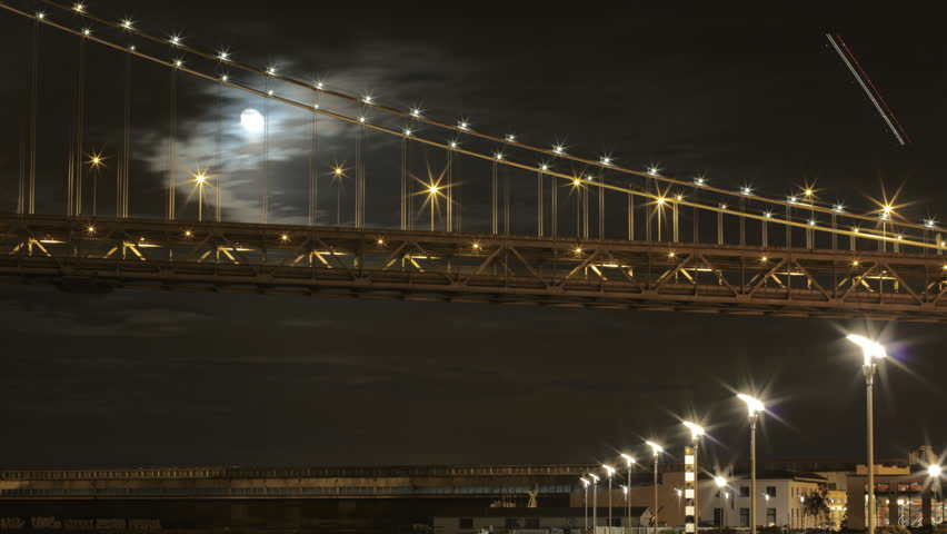 Night time timelapse of Moon passing behind the Bay Bridge in San Francisco.
