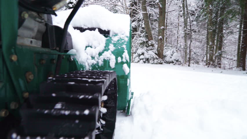 A big tank slowly moving on the thick white snow during a winter season in the city