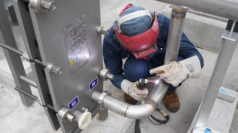 Welder arc welding metal stainless pipe for cooling water system in the factory