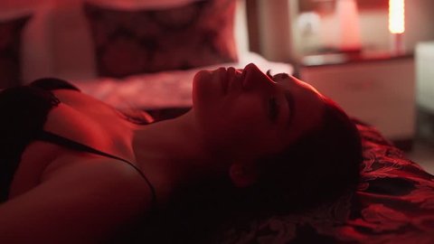 A girl in erotic black underwear lies on a bed and poses sexually in front of the camera