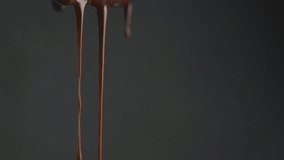 Stream of melted chocolate pouring on a black background. Slow motion video 120 fps