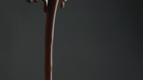 Stream of melted chocolate pouring on a black background. Slow motion video 120 fps