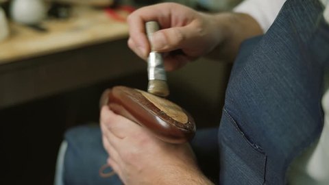 Shoe maker soaks the glue, master, craftsman, workman is manufacture, produce, make shoes in small atelier, factory. hammer knocking on shoes, Close up
