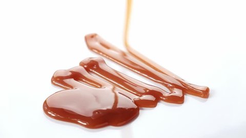 Pouring caramel syrup on white background