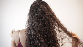 back of the woman with long brown curly hair with healthy shine. Woman on her back playing with her curls. young woman with curly hair on her back stroking them with her hands - Powered by Shutterstock - Get 15% off with code: PIKWIZARD15