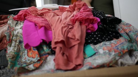 Close up of clothing piling up on bedroom bed - hoarding concept