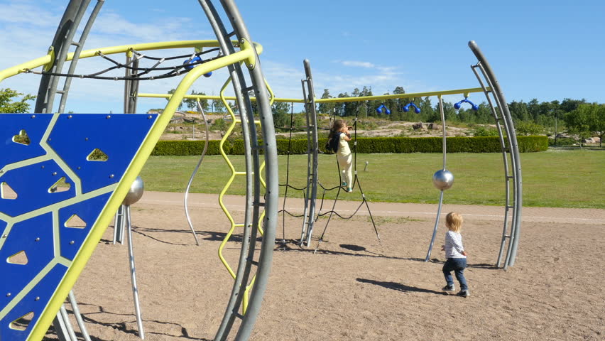 Children playing on playground, family walking in park. Two little girls playing and walking