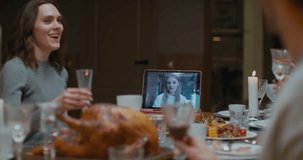 Family having a video call with relative during thanksgiving dinner, happy family greeting a remote guest. 4K UHD 60 FPS SLOW MOTION Blackmagic RAW