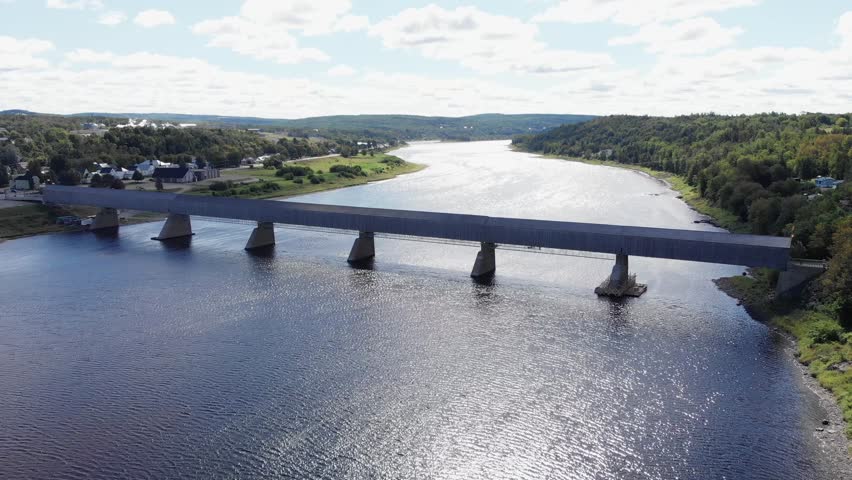Aerial, drone shot, over a blue river and the worlds largest covered bridge, on a sunny day, in New Brunswick, Canada Royalty-Free Stock Footage #1022750194