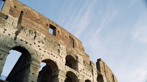 Panning shot on the Coliseum in Rome against a blue sky with clouds on a bright sunny day. Wide shot on 4k RED camera.