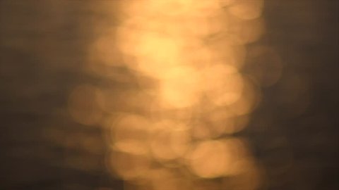 Defocused Blurred golden water surface at sunset, background. Abstract Blinking sea, river or ocean blurry backdrop. Bokeh. 4K UHD video Slow motion