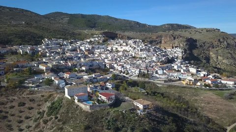 Aerial view of a traditional spanish white village in the mountains with a big chuch.