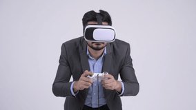 Young bearded Indian businessman playing games and using virtual reality headset