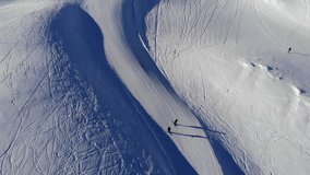 Aerial - Top down rear view of skier going down the empty ski slope (slow motion)
