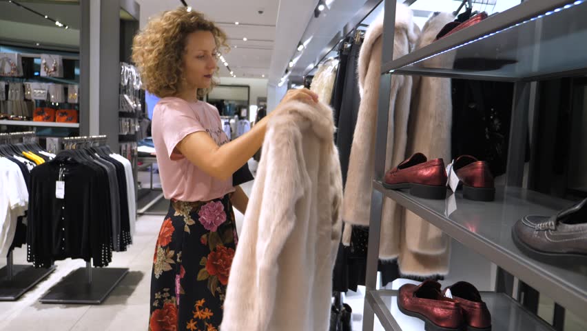 Young Female Customer Choosing Faux Fur Coat In Women`s Clothing Store Royalty-Free Stock Footage #1022804353