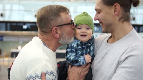 Meeting at the airport. Grandfather, son and grandson. Three generations of the same family are happy to see each other. Father's Day, Family Day