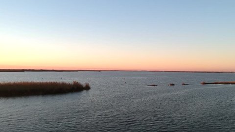 Wide shot of Louisiana bayou as sun sets on clear day with fisherman relaxing