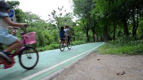 People biking bicycle on bike lane in a park of Thailand.